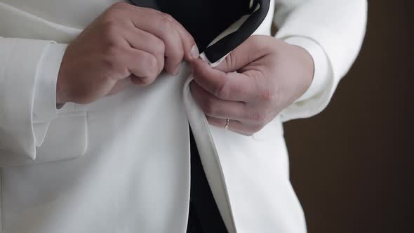 Groom Buttoning Jacket Man in Suit Fastens Buttons on His Jacket Preparing to Go Out