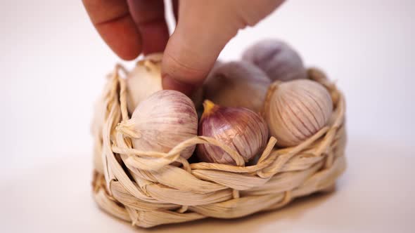 Garlic in a Wicker Basket, on a White Background. Dried French Garlic. Red Garlic.