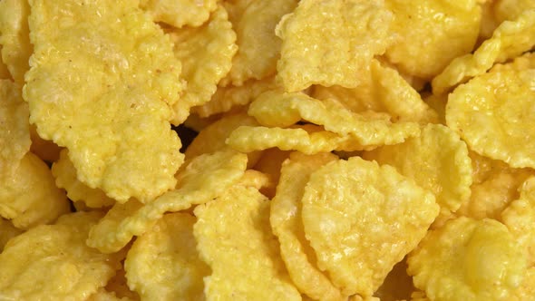 Crispy corn flakes rotating in macro, dry healthy breakfast. Honey cornflakes for healthy cereal