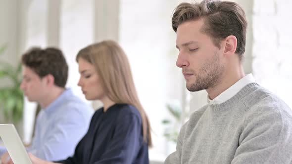 Portrait of Attractive Creative Man and Smiling at the Camera in Office