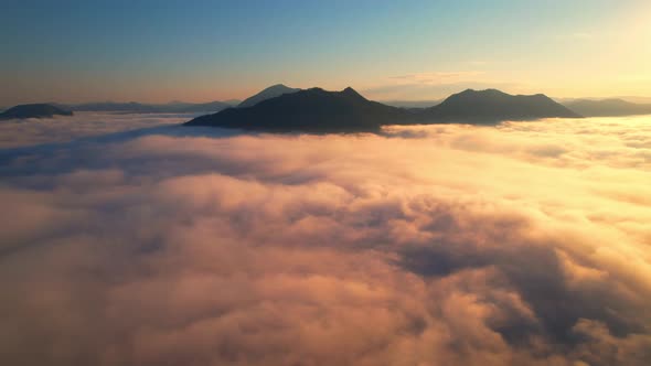 4K aerial view over a misty mountainous area. The great golden sun in the morning