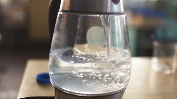 Slider Shot of a Transparent Kettle with Water Boils