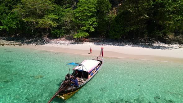 aerial drone circling a thai longtail boat anchored in the turquoise blue water of Ko Kai Island in