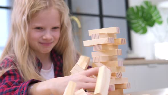 Children Playing Wooden Block Removal Tower Game at Home