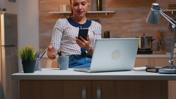 Woman Taking Break and Typing on Smartphone in the Kitchen