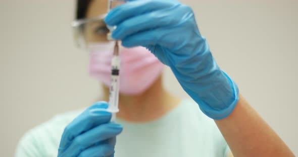 Doctor scientist protective gloves and mask holding glass vial with injection liquid. Vaccination