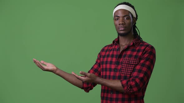 Young Handsome African Man with Dreadlocks Against Green Background