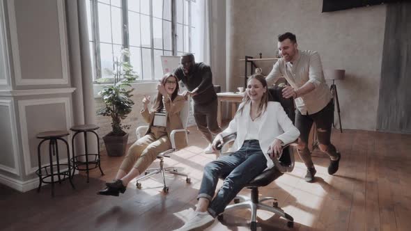 Cheerful Colleagues Having Fun in Office Chairs. Team Building