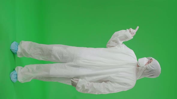 Man Wearing Protective Uniform PPE And Pointing To The Side In The Green Screen Studio