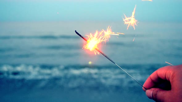 Burning One Bengal Fire in Hand Against the Background of a Sea Ocean Waves