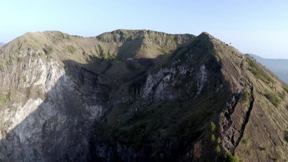 Mount Batur active volcano summit in Bali Indonesia with people visiting crater ridge, Aerial pan le