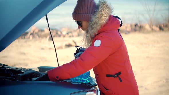 Woman Driver Pours Blue Winter Windshield Washer Fluid From Bottle. Add Windshield Washer Fluid.