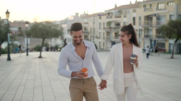 Trendy Hispanic Couple Drinking Takeaway Coffee While Strolling on Street