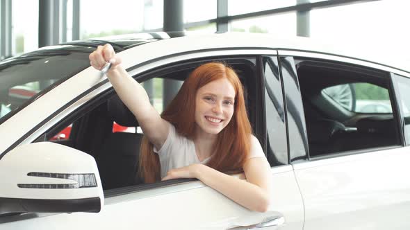 Overjoyed Driver Woman Smiling and Showing New Key While Sitting in Car Showroom