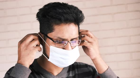 Young Asian Man Putting Surgical Face Mask Indoor