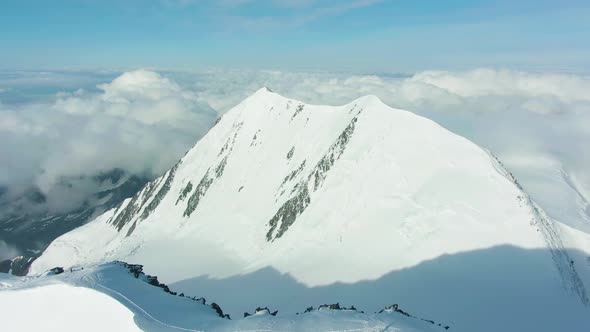 Snowy Top of Mountain in European Alps in Sunny Day. Aerial View