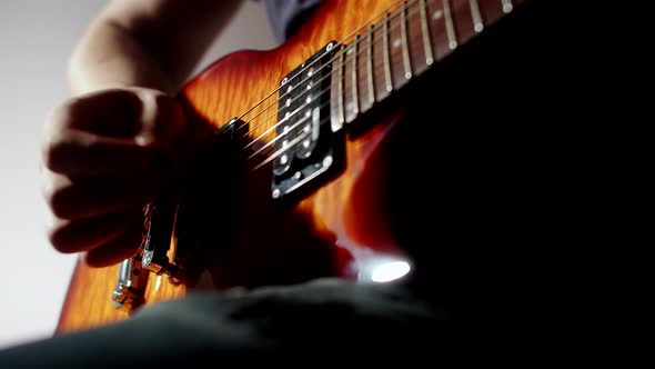 Male Musician Plays Strings of an Electric Guitar Holding Plectrum in Fingers Closeup Hands