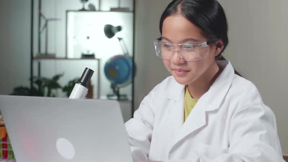 Young Asian Scientist Girl Using Lap Top Computer In Laboratory Experiment With Liquid