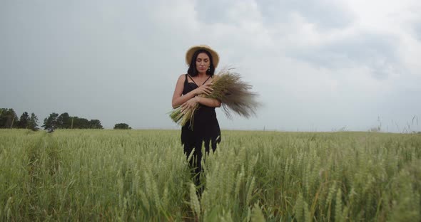 Girl In A Straw Hat Walks On A Wheat Field