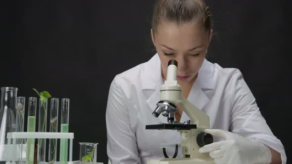 Young Microbiologist Works on Research Looks Through Microscope in Laboratory