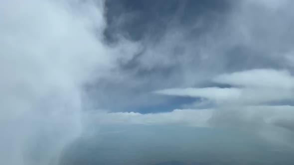 Stunning pilot point of view while flying at cruise level through fluffy white clouds in a summer de