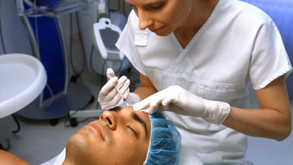 Doctor inserting facial injection on male patient forehead