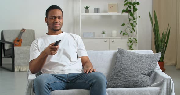 Afro American Guy Fan Emotional Bachelor Wears Casual Clothes at Home Sitting in Modern Living Room