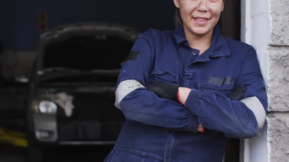 Portrait of female mechanic with arms crossed smiling at a car service station