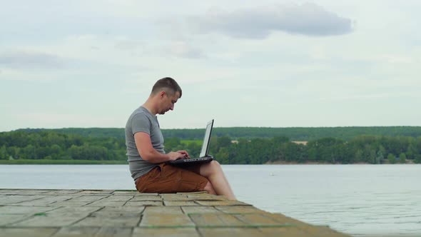 Man on the pier working on a laptop. Work on vacation