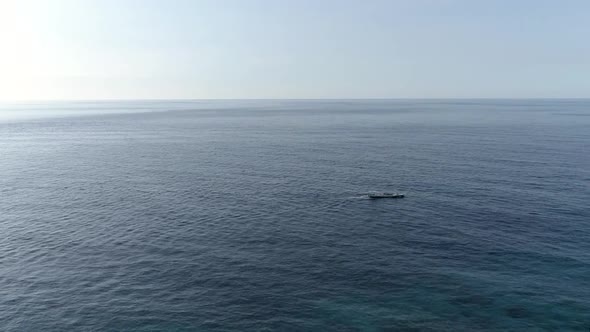 Aerial view of single traditional boat anchored next to Maldives island.