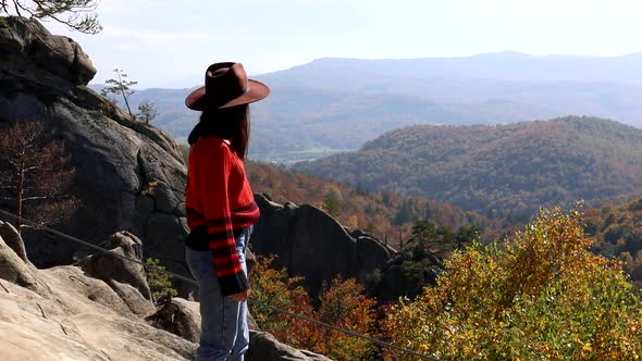 Woman Hiker Traveler Looking at Autumn Forest From the Big Rock