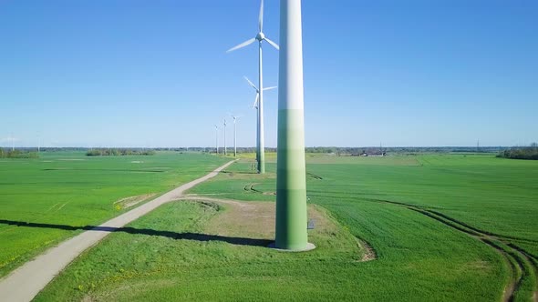 Aerial view of wind turbines generating renewable energy in the wind farm, sunny spring day, low fly