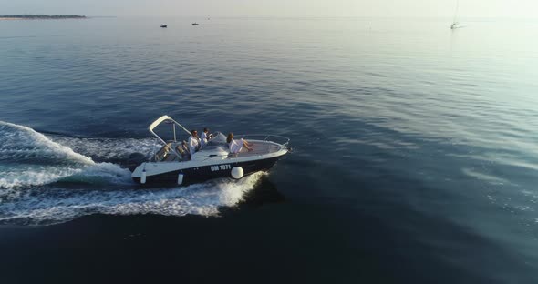 A Drone Shot of a Happy Family on a Summer Vacation Driving a Luxury Boat on the High Seas in the