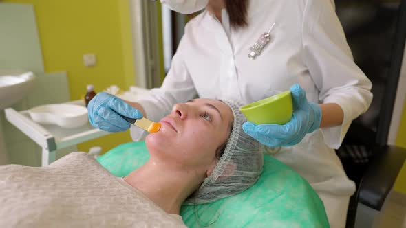 Female Cosmetologist Performing Fruit Acid Peeling Procedure for Young Women in Beauty Clinic