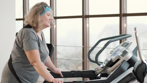 Overweight Woman Exercising on a Treadmill at a Gym