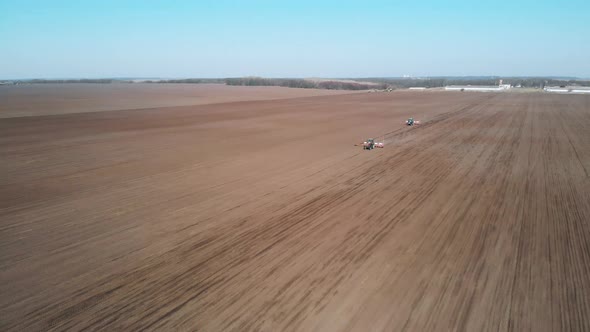 Two tractors fertilize a field