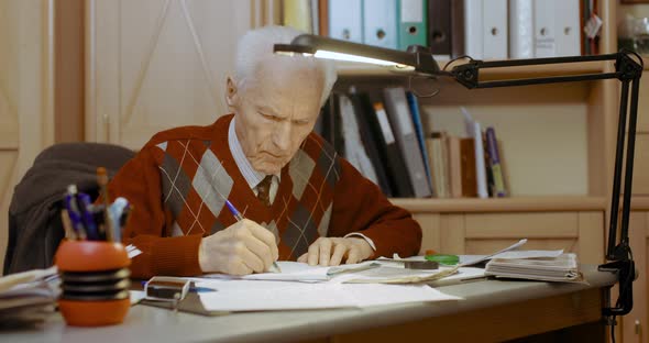 Senior Businessman Writing on Paper at Table in Office