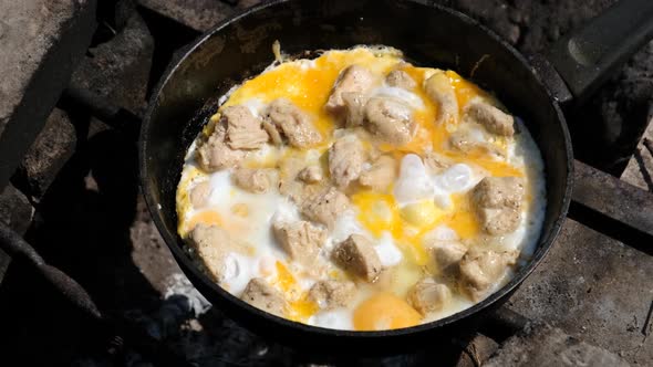Cooking Scrambled Eggs with Chicken Meat on Tourist Campfire Frying Pan Nature