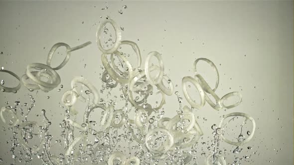 A Bunch of Onion Rings with Water Fly Up and Rotate in Flight