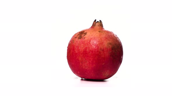 Ripe Red Pomegranate in Drops of Water Rotates on White Background Isolate. Beautiful Exotic Berry