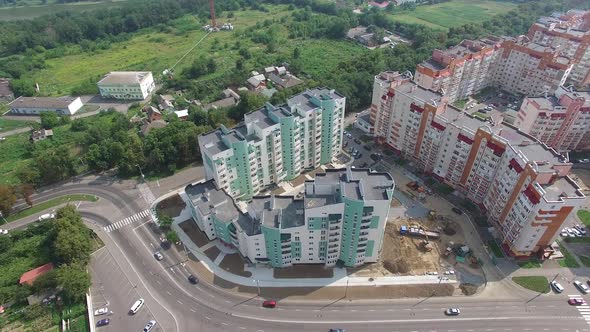 Flying over the modern residential buildings and green trees in the town.