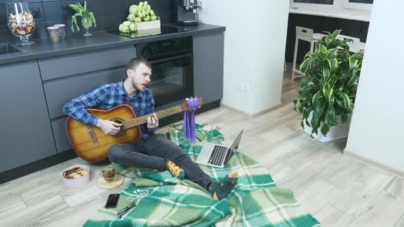 Young musician is singing and playing lyrical ballads on acoustic guitar