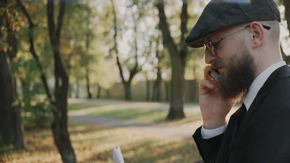 Businessman Talks on the Phone Checks Documents Wearing Hat and Glasses