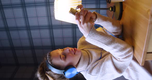 A Young Woman in Headphones Listening to the Music Singing and Online Messaging Via Smartphone