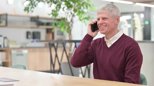 Middle Aged Man with Laptop Talking on Smartphone