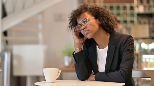 Pensive African Businesswoman Drinking Coffee and Thinking in Cafe