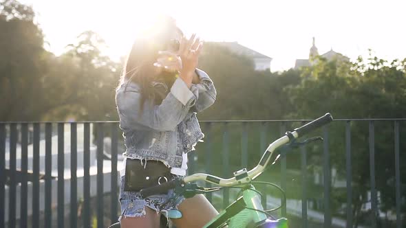 Woman with Long Hair in Fashion Jeans Clothes Sitting on Her Bike Sings and Dances