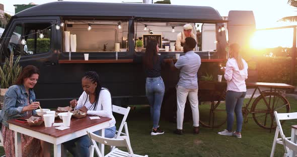 Multiracial people eating food truck gourmet meal outdoor - Healthy dinner and summer concept
