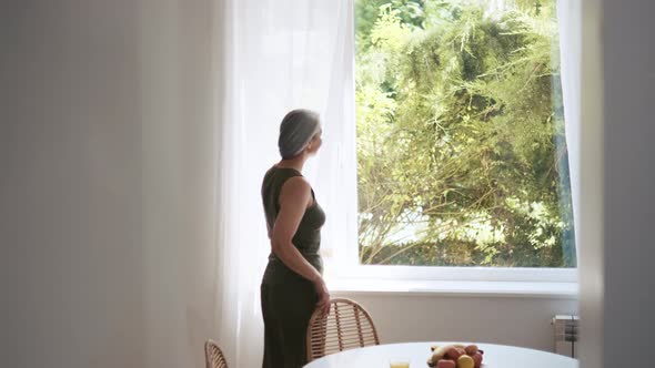 Back view of grey-haired woman looking at window