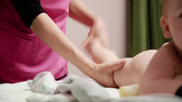 The masseuse gives a leg and foot massage to baby (boy) 14